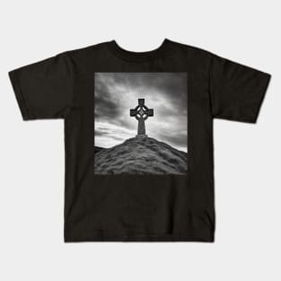 Ancient Celtic Cross on a Burial Mound hill on a hill beneath a stormy, angry sky Kids T-Shirt